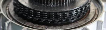 Close up of damaged automatic transmission clutch pack with burnt friction discs and bent steel plates